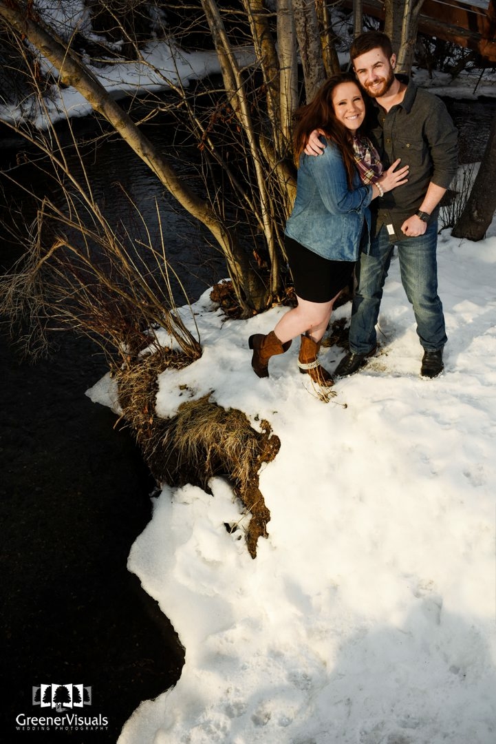 couple-on-snowy-bozeman-creek-bank-Story-Mill-Park-Winter-Engagement-Portrait