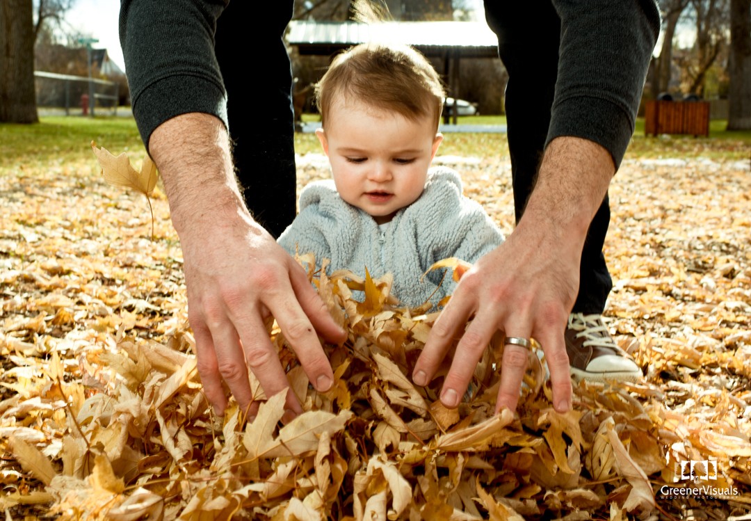 father-buries-daughter-in-leaves-during-toddler-Fall-Family-Portraits