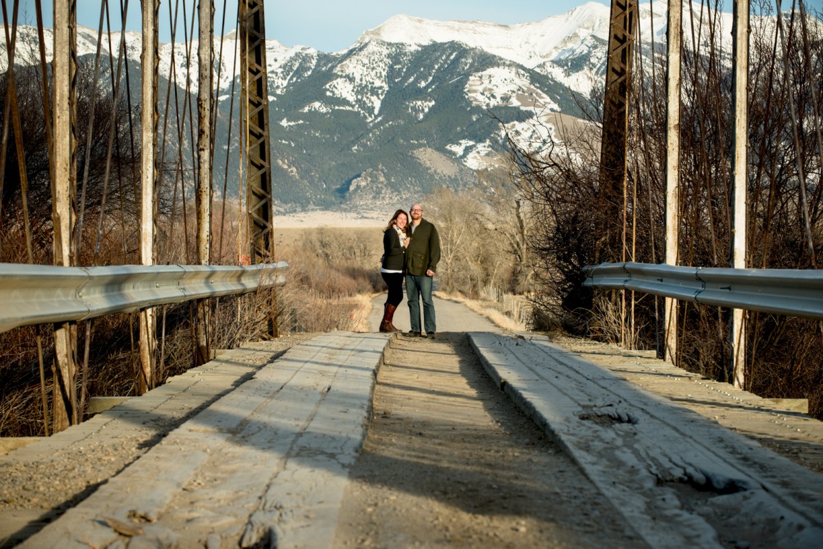 couple-embrace-on-river-bridge-Ennis-Montana-Engagement-Photos