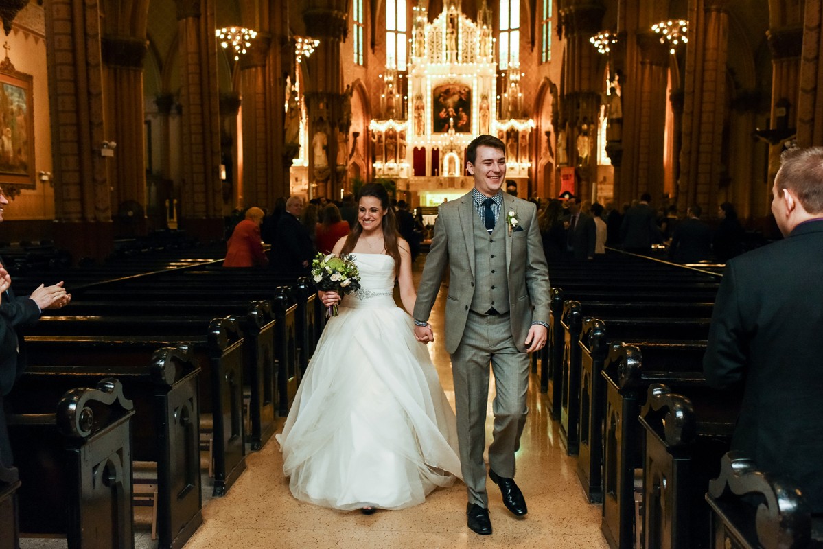 newlyweds-walk-down-aisle-of-church-of-the-holy-family-chicago