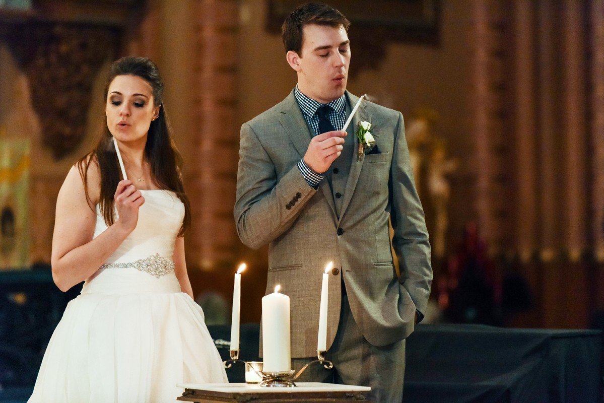 bride-and-groom-blow-out-candles-during-church-of-the-holy-family-ceremony