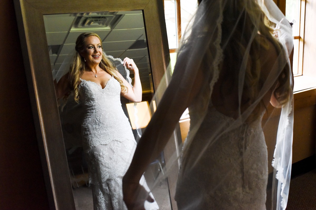 bride-smiles-at-dress-in-mirror-Whitefish-Mountain-Resort-Wedding
