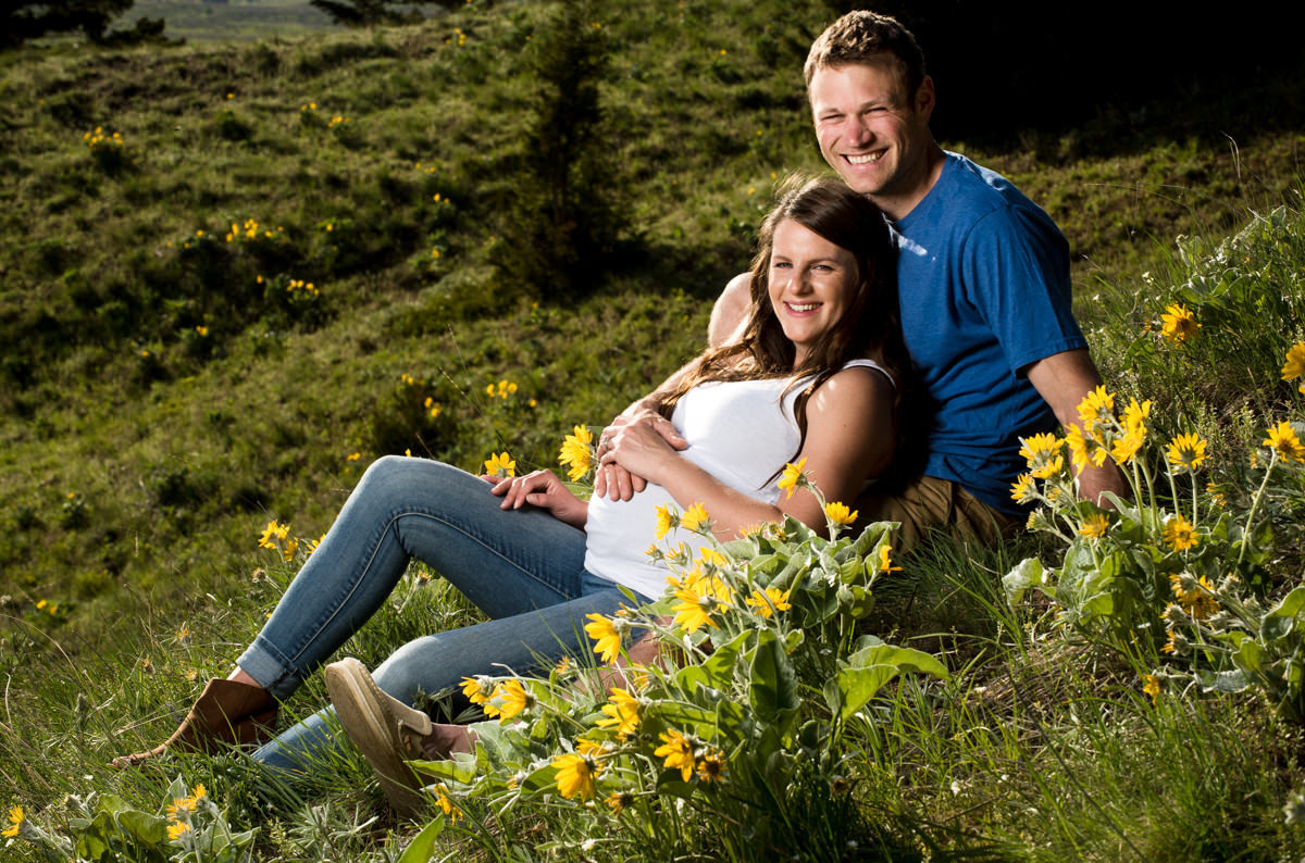 expecting-couple-lay-in-yellow-flowers-during-Bozeman-Maternity-Family-Portraits-session
