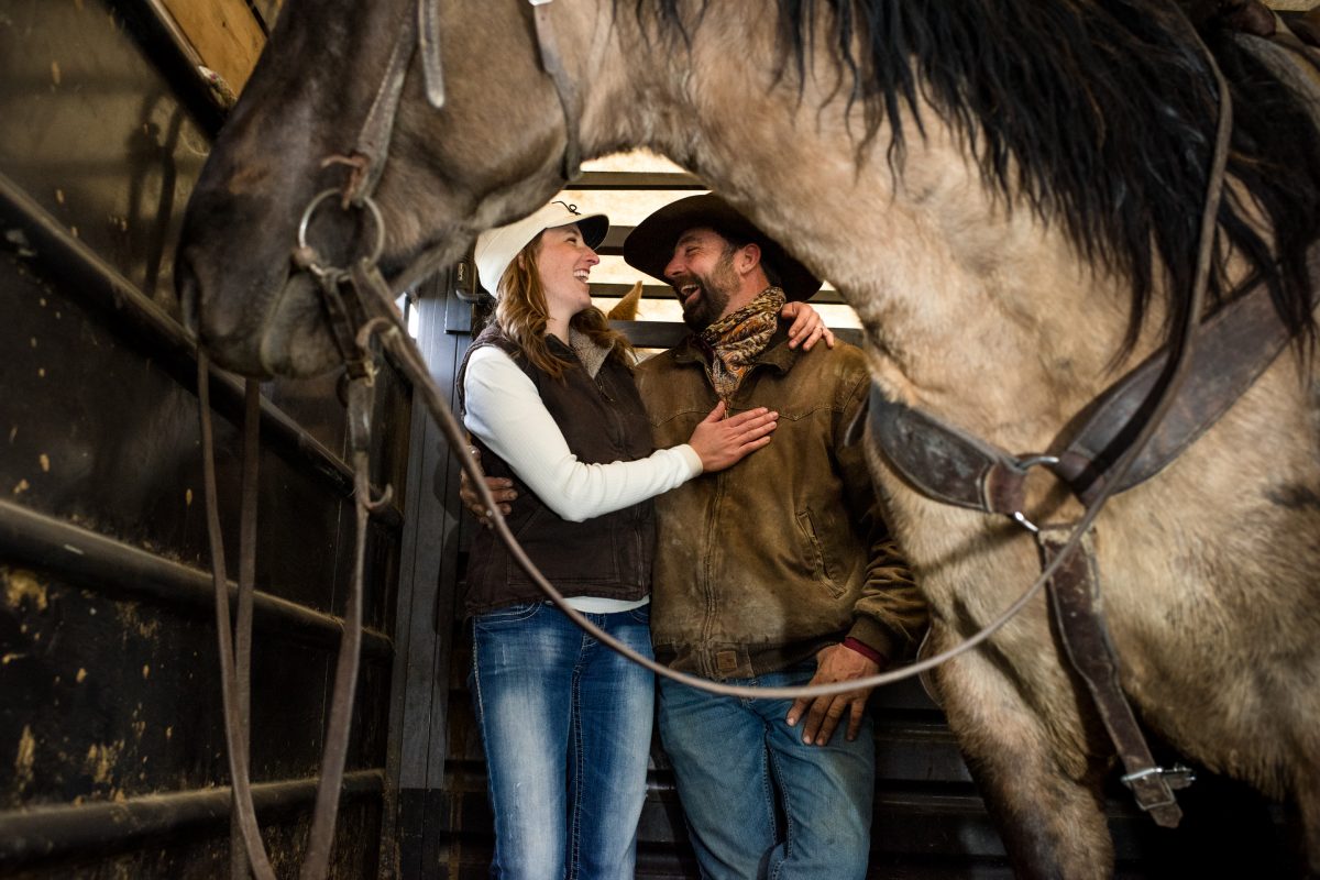 cowboy-couple-embrace-in-horse-trailer-Horseback-Riding-Engagement-Portraits