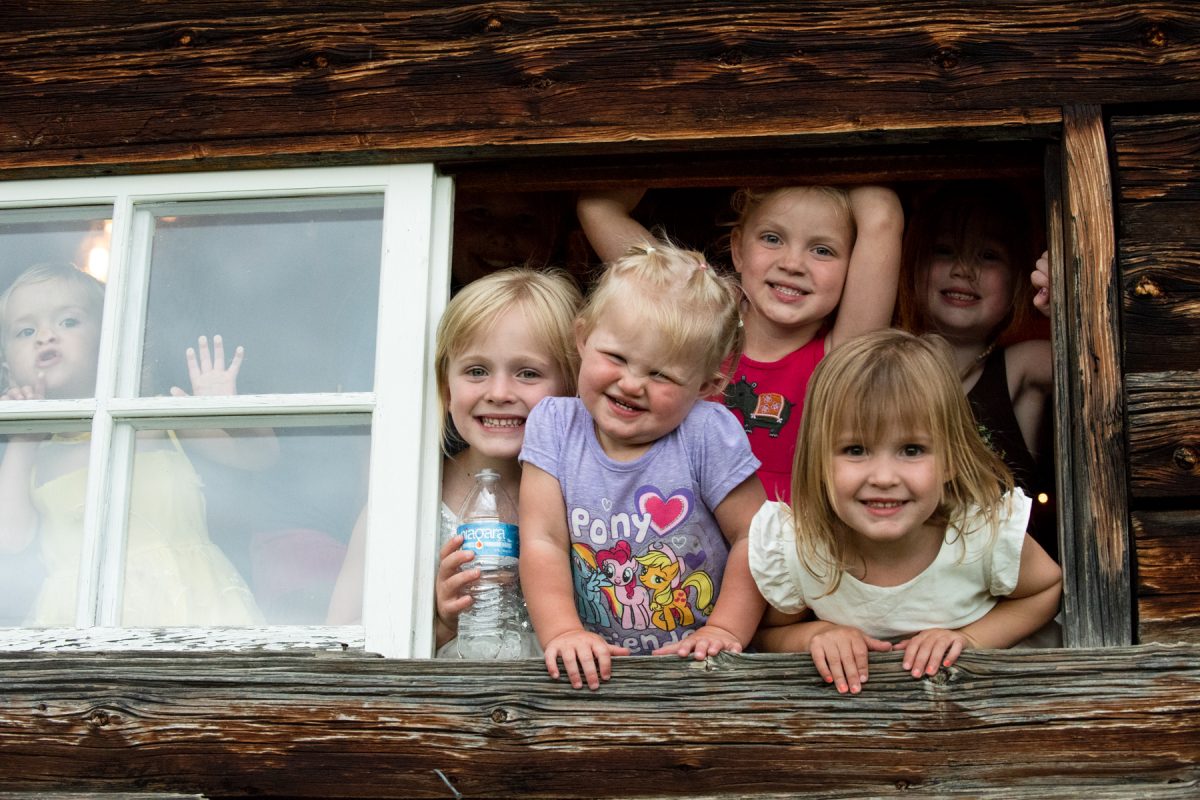kids-smile-out-of-window-at-Springhill-Pavillion-Bozeman-Wedding-Photography