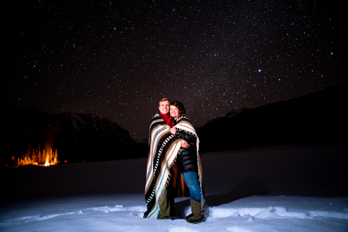 engaged-couple-stand-on-reservoir-under-stars-during-Hyalite-stargazing-engagement-portraits