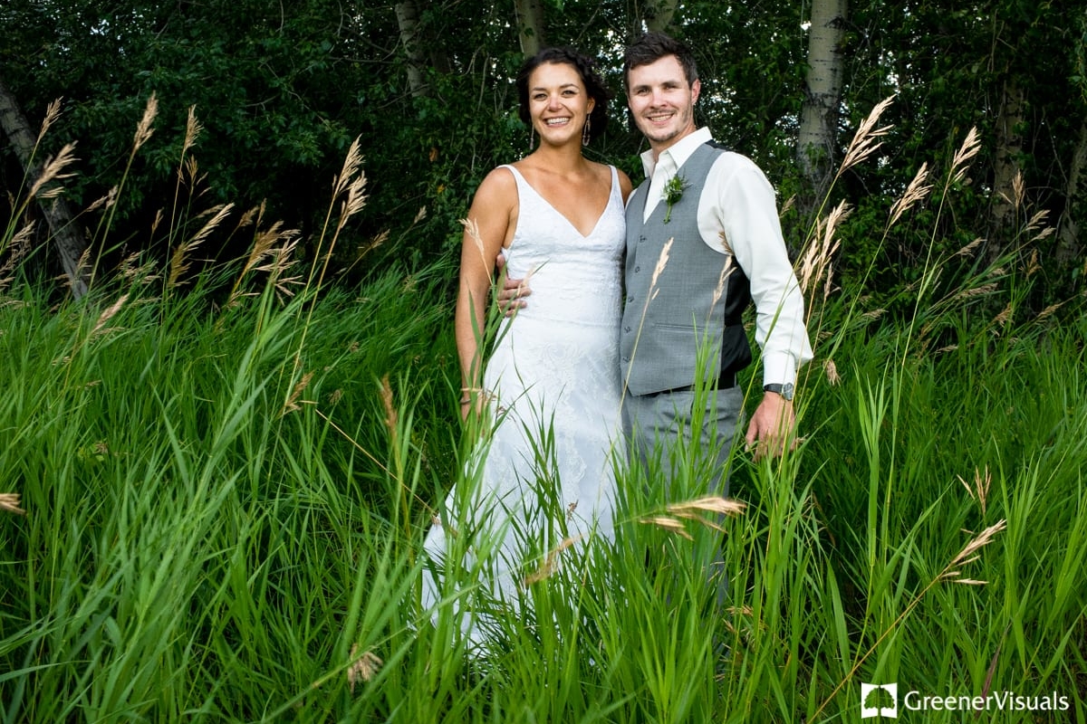 bride-and-groom-smile-in-tall-grass-during-Countryside-Bozeman-Montana-Wedding