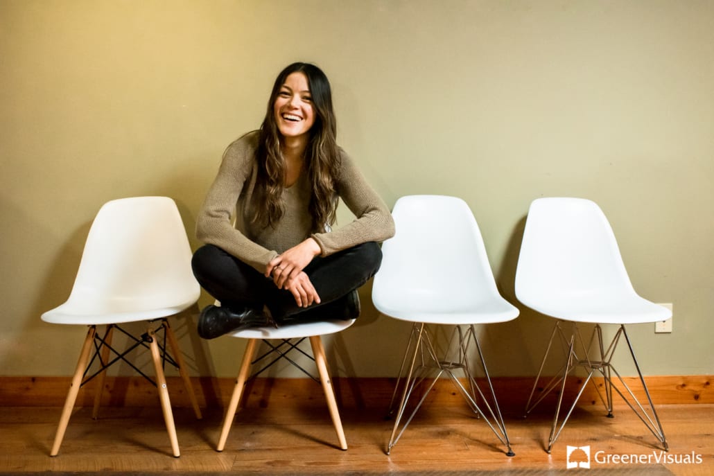 smiling-woman-sits-crossed-legged-on-white-chairs-Hood-River-Oregon-Business-Portraits