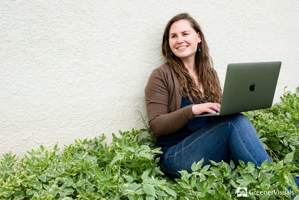 Katie-Smith-sitting-in-green-leaves-against-white-wall