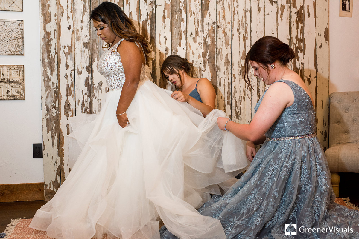 bride-puts-on-wedding-dress-with-bridesmaids