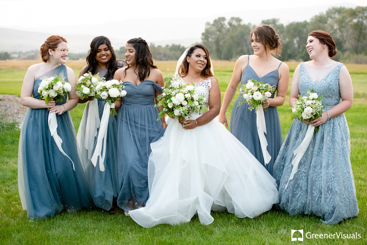 bride-with-bridesmaids-in-blue-dresses-laughing-outside