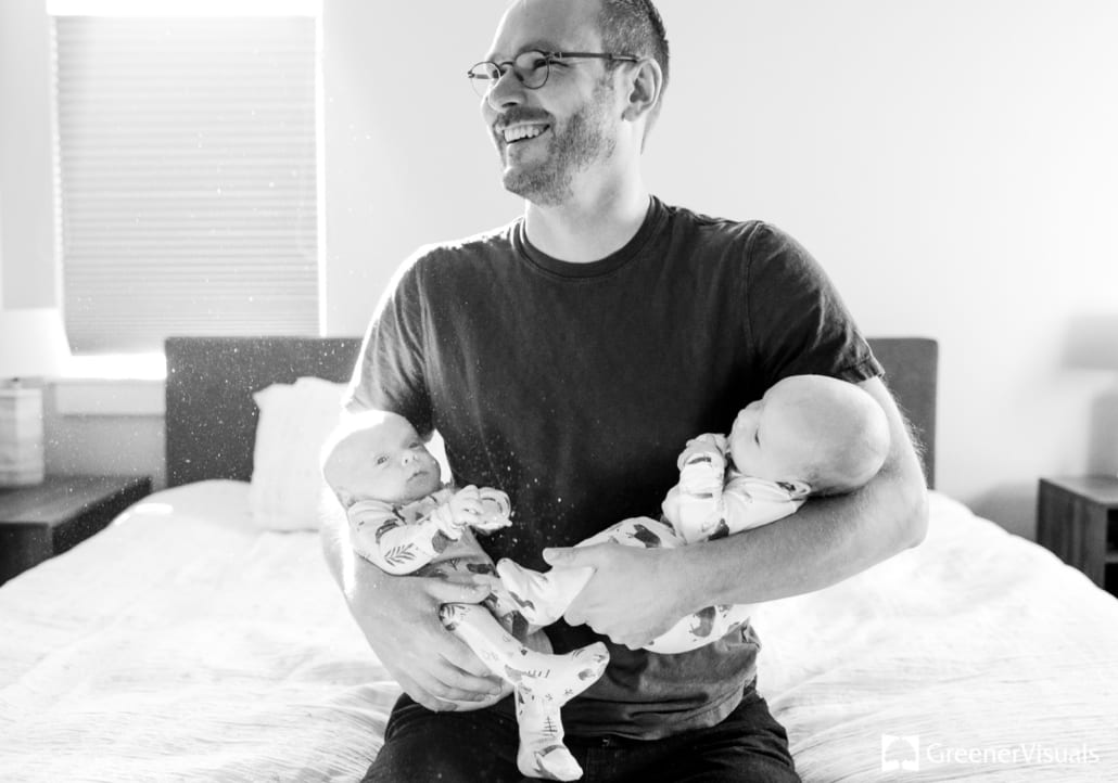 new-father-holding-newborn-twin-boys-smiling