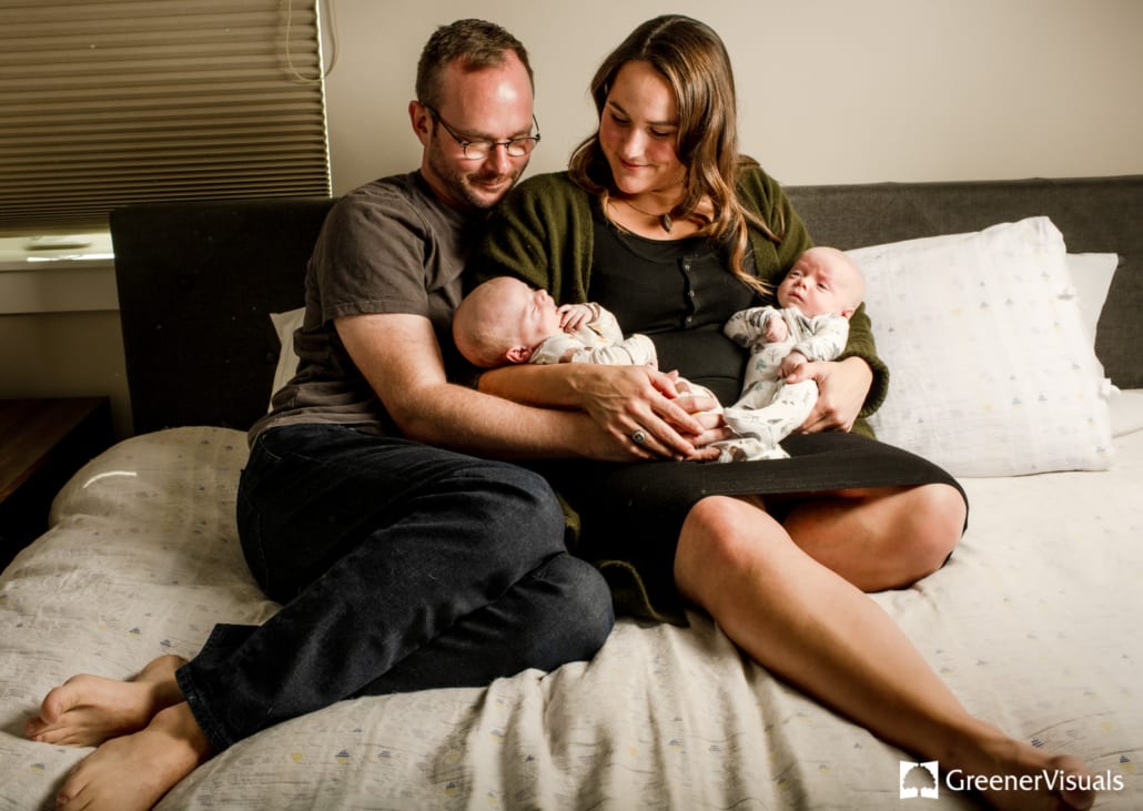 new-parents-holding-newborn-twin-boys-in-bed
