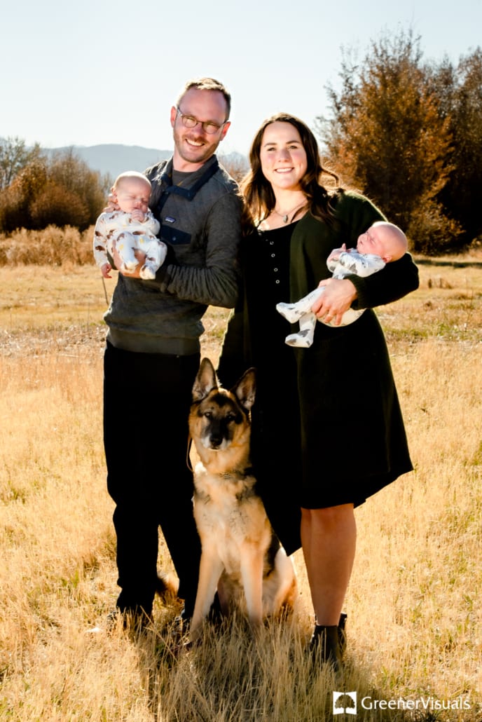 new-parents-holding-newborn-twin-boys-outside-with-dog
