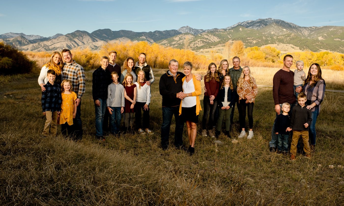 Large-group-family-portrait-in-golden-field-near-mountains