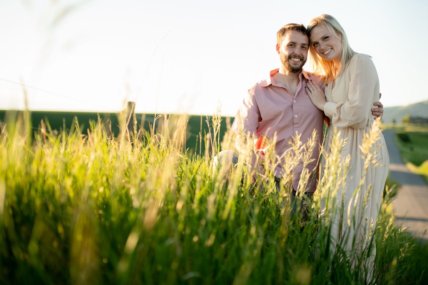 Newly-engaged-couple-in-grassy-field-at-sunset