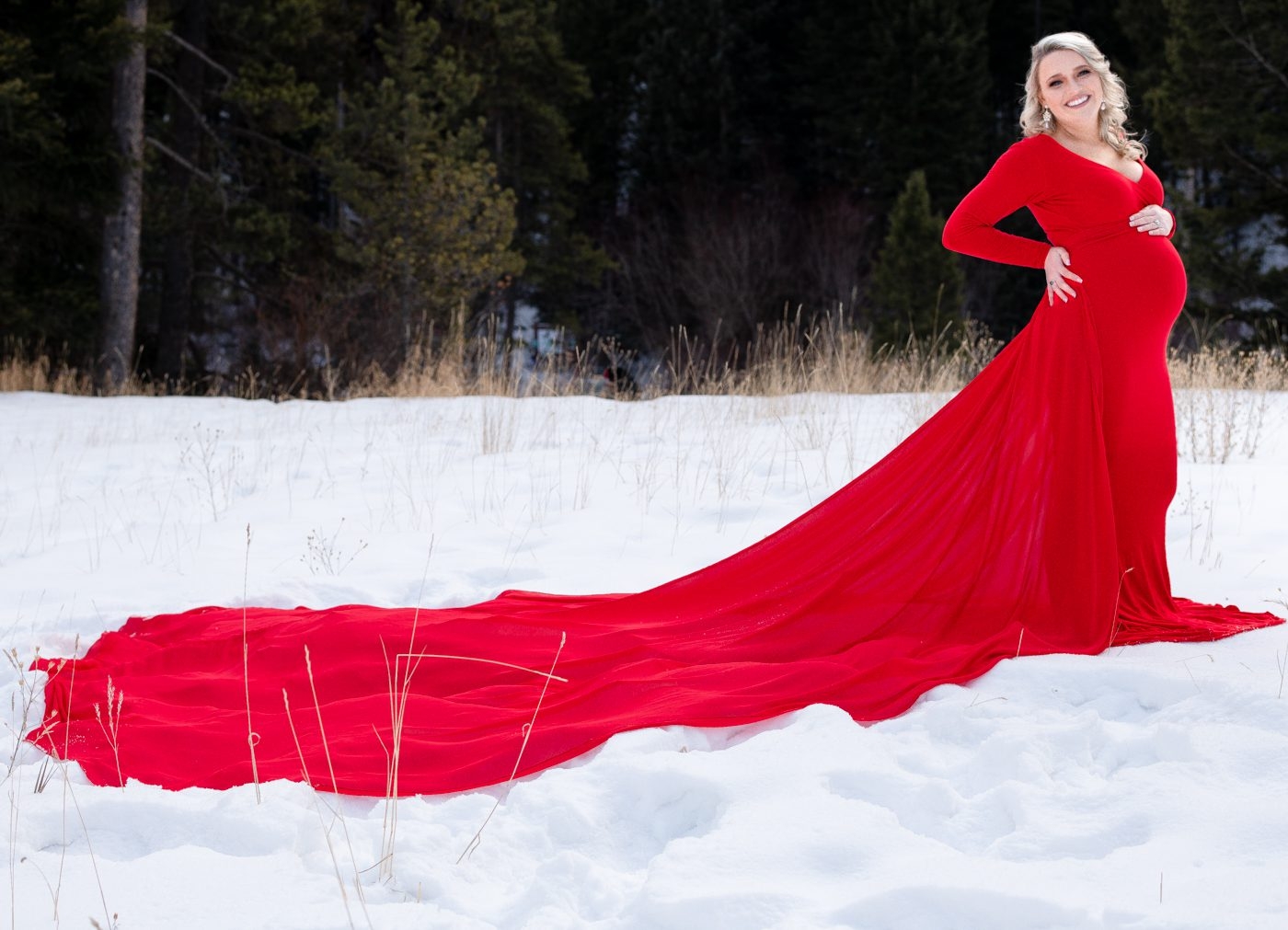 Maternity-mother-in-red-dress-with-long-train-in-snow-field