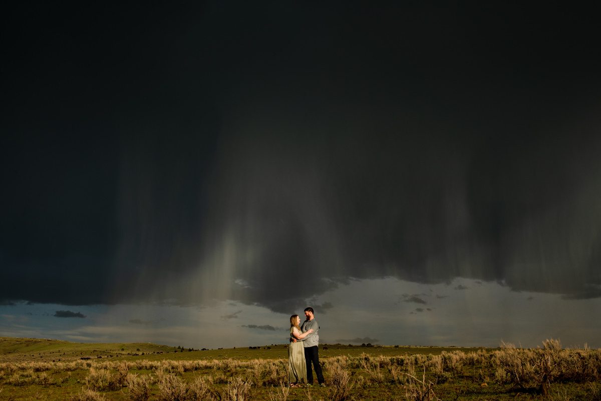 couple-in-sunshine-with-dark-rainclouds-during-Montana-Ruby-Valley-Rainstorm-Engagement-session