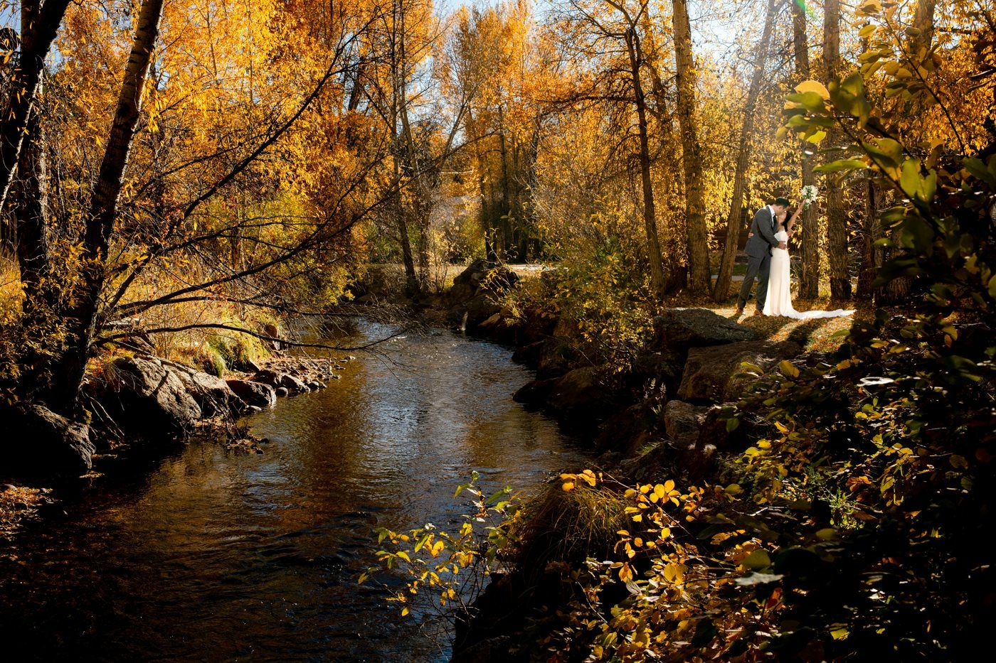 wedding-couple-by-river-in-golden-leaves-at-Fall-River-Village-Sky-View-Lodge-Estes-Park-Colorado