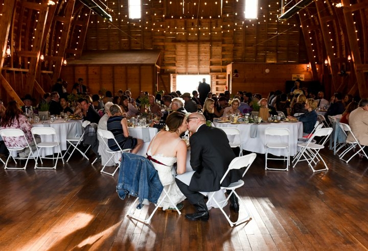 bride-groom-kiss-at-table-during-Big-Yellow-Barn-wedding