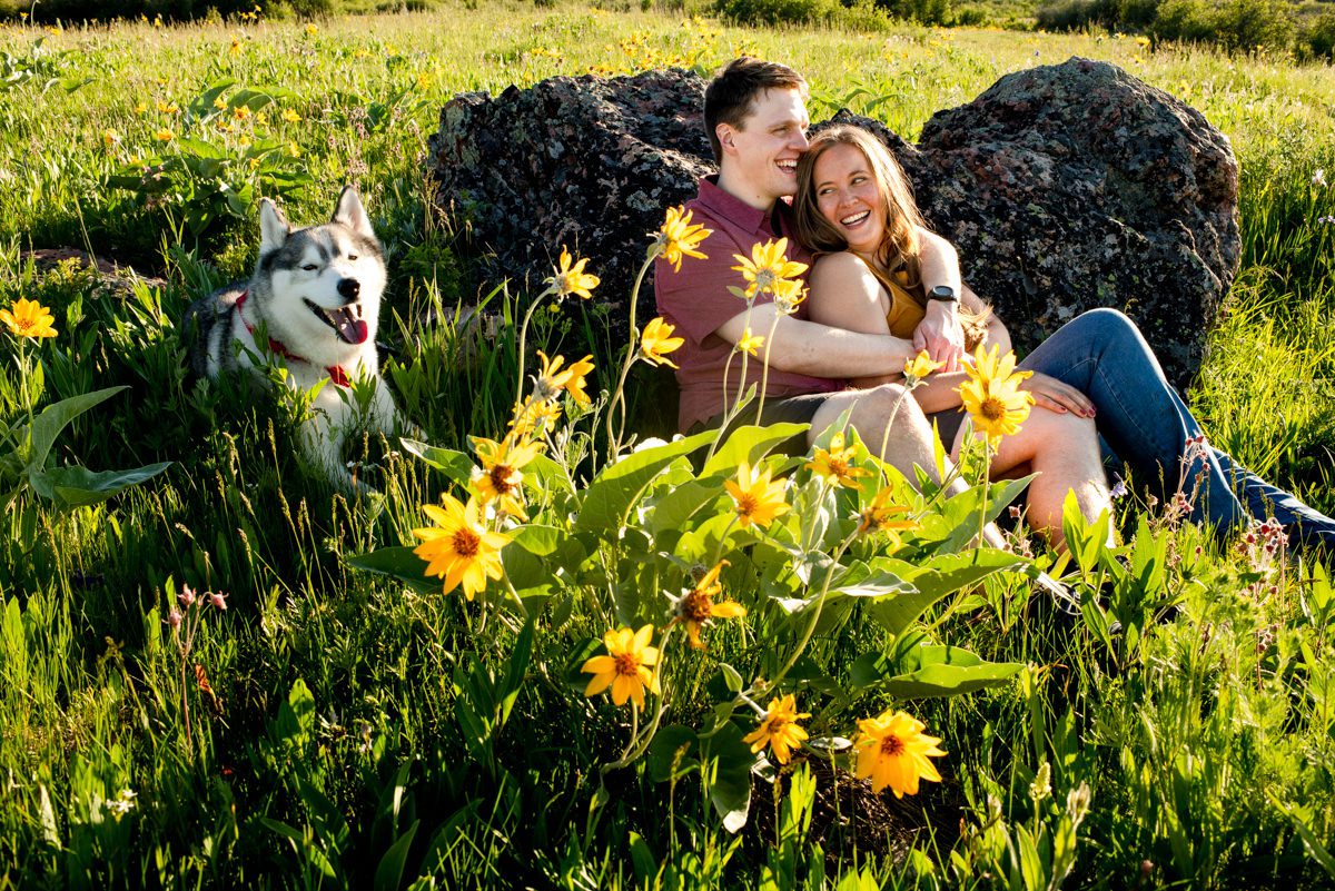 engaged-couple-laugh-watching-sunset-together-at-Mount-Ellis-Trailhead-engagement-portraits