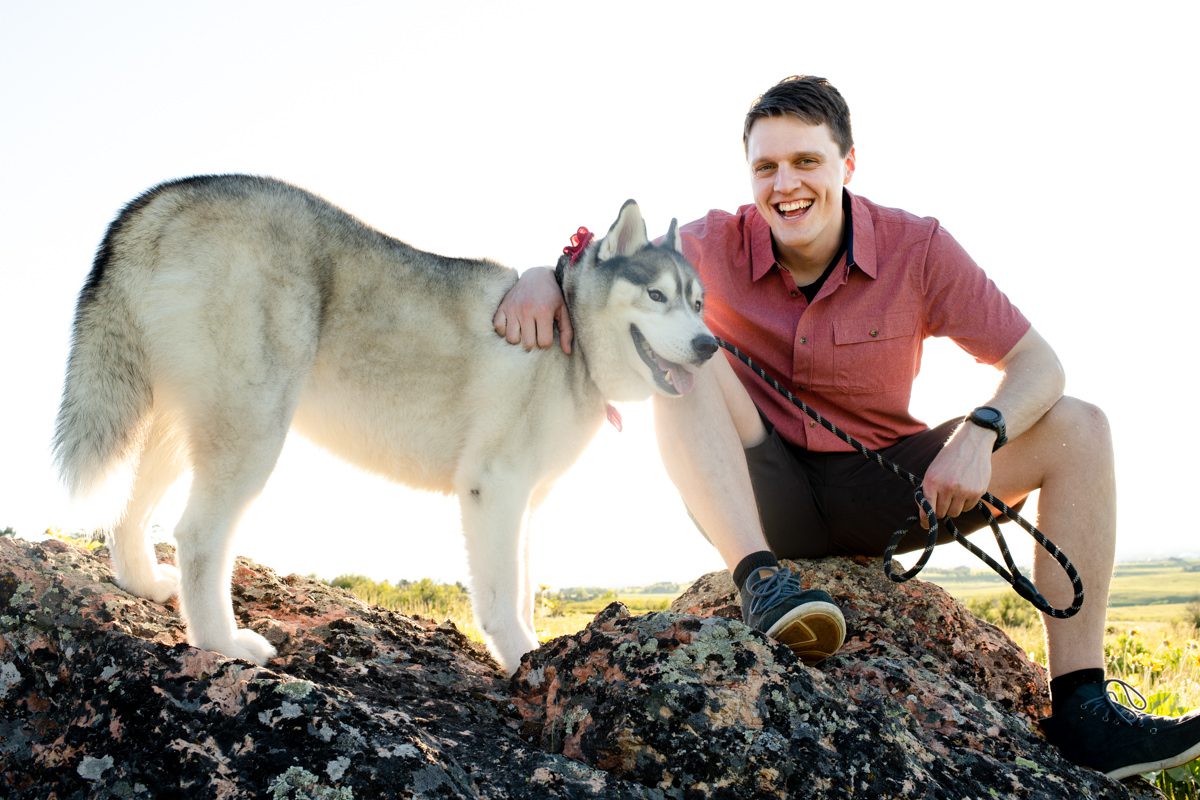 man-sitting-with-his-dog-during-Mount-Ellis-Trailhead-engagement-portraits