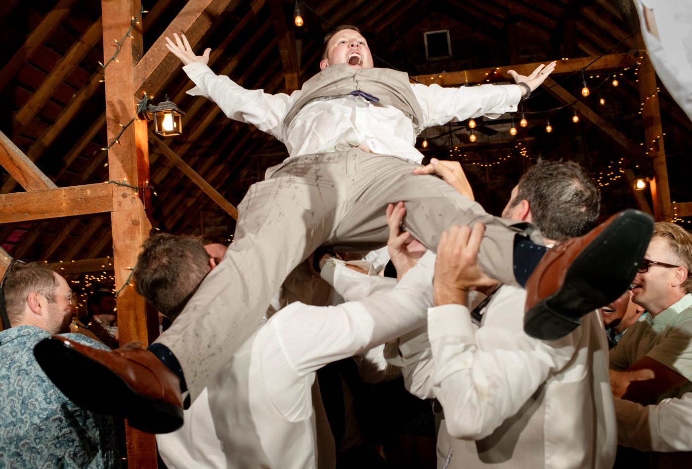 groom-tossed-in-air-by-groomsmen-at-roys-barn
