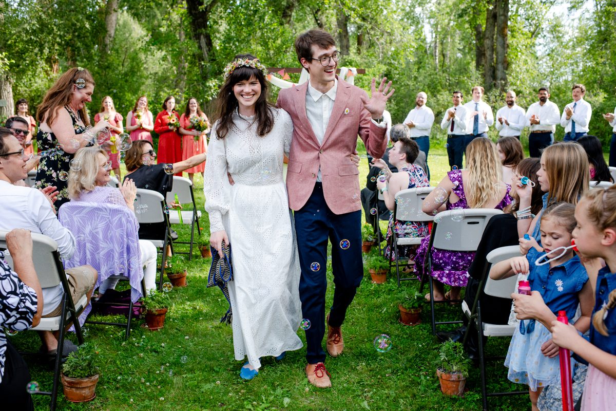 newlyweds-walk-through-bubbles-at-Gallatin-River-Hideaway-wedding