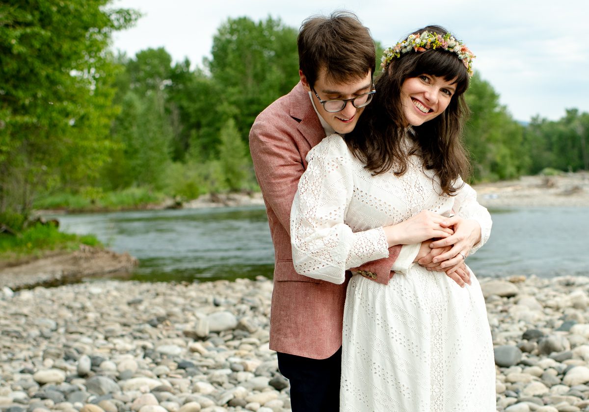 Bride-and-groom-embrace-on-river-bank-at-Gallatin-River-Hideaway